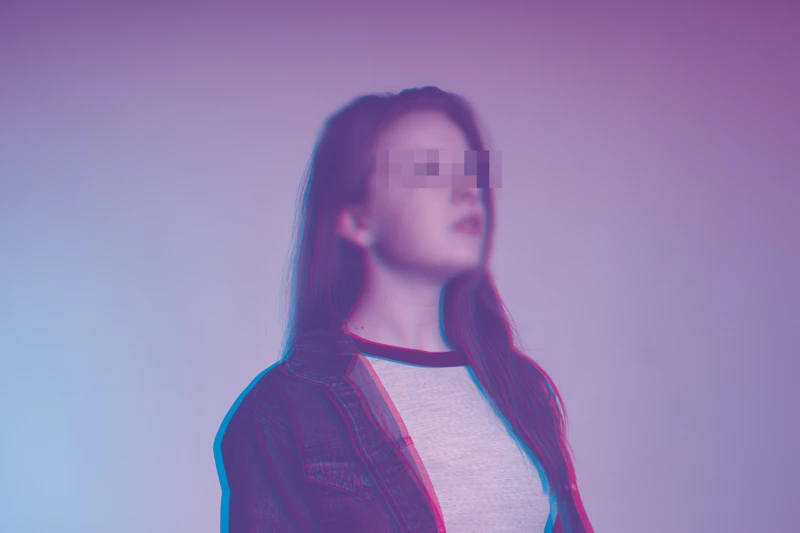 Portrait of a young woman with long hair wearing a denim jacket and a light t-shirt, standing against a purple-blue gradient background; the image features a glitch blur effect over the eyes, color distortion outlining the model's edges, and an overall slightly blurred, dreamlike focus. Portrait of a young woman with long hair wearing a denim jacket and a light t-shirt, standing against a purple-blue gradient background; the image features a glitch blur effect over the eyes, color distortion outlining the model's edges, and an overall slightly blurred, dreamlike focus.